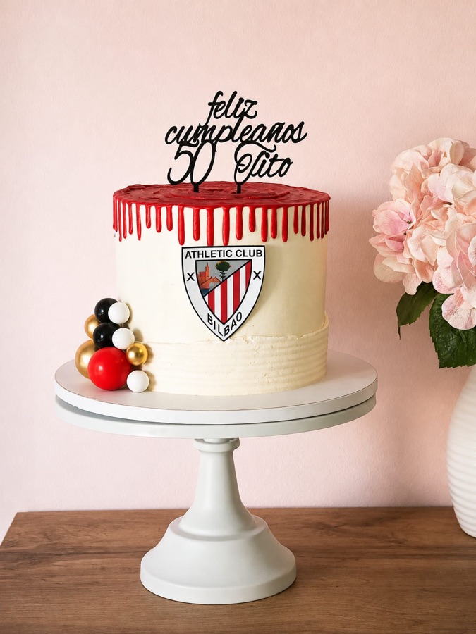 Tarta marfil con el escudo de un club de fútbol y goteo rojo en el borde