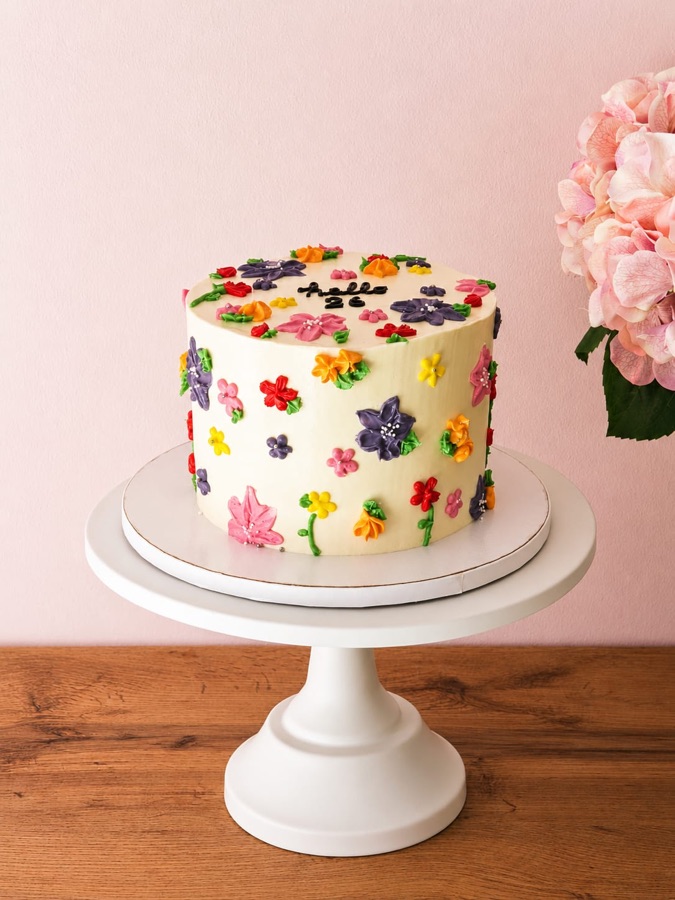 Tarta marfil cubierta de flores pequeñas de buttercream de muchos colores