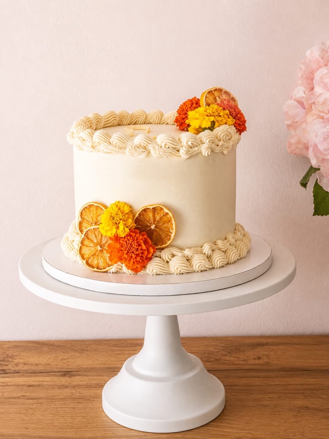 Tarta marfil con piping vintage, naranja deshidratada y flores naranjas