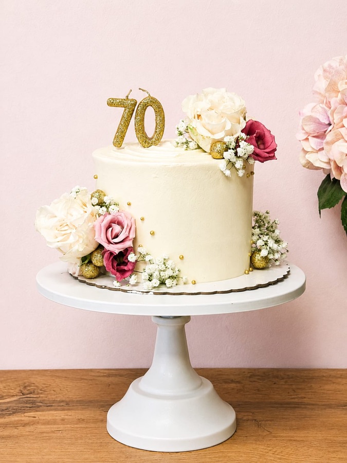 Tarta marfil con flores frescas en rosa y blanco y número setenta dorado