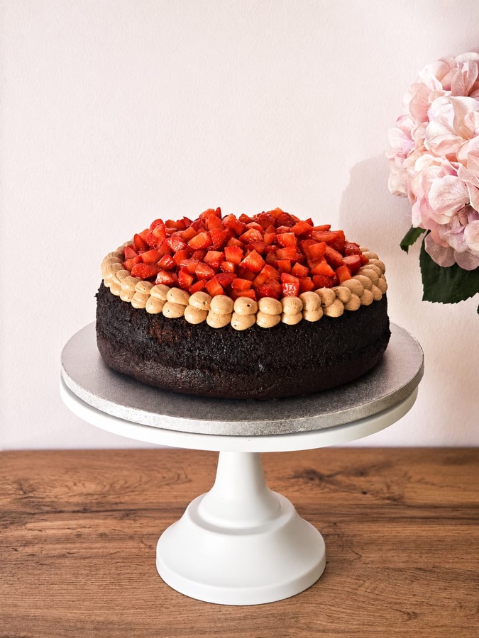 Tarta de chocolate con fresas frescas troceadas encima y borde de nata montada