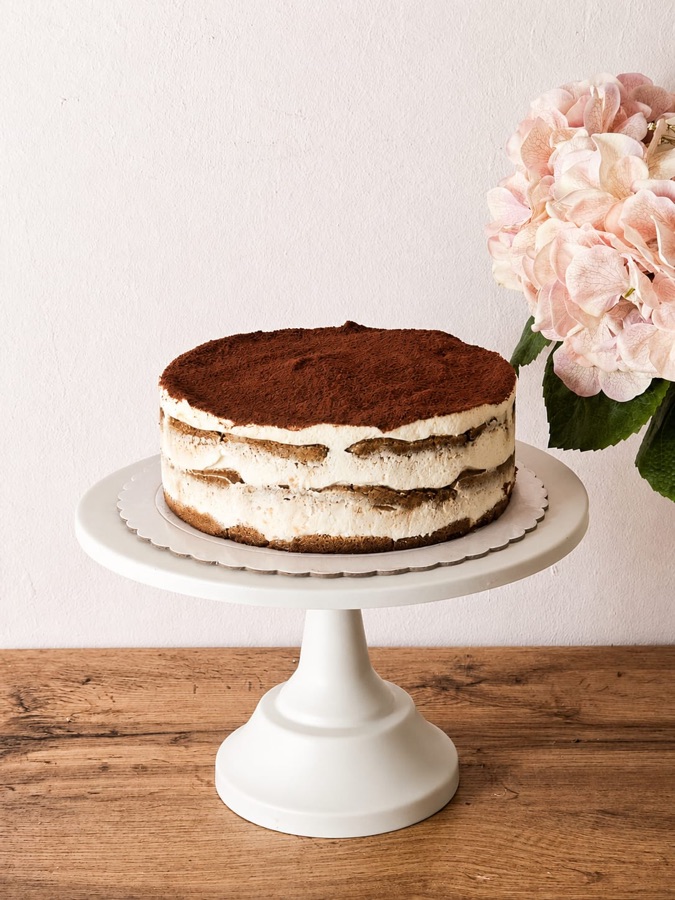 Tarta de tiramisú con capas visibles de bizcocho y crema y cacao espolvoreado