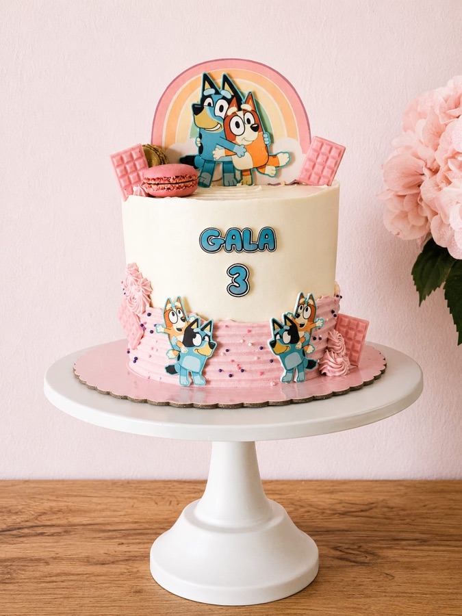 Tarta de Bluey en buttercream rosa y blanco con figuras de los personajes