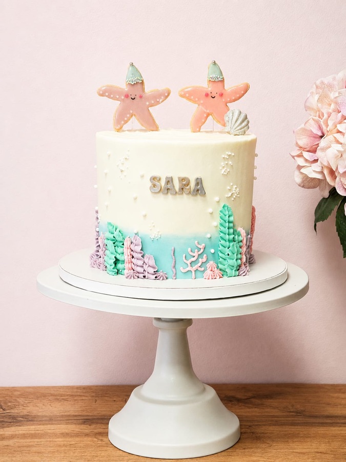 Tarta de fondo marino en tonos pastel con estrellas de mar, conchas y algas