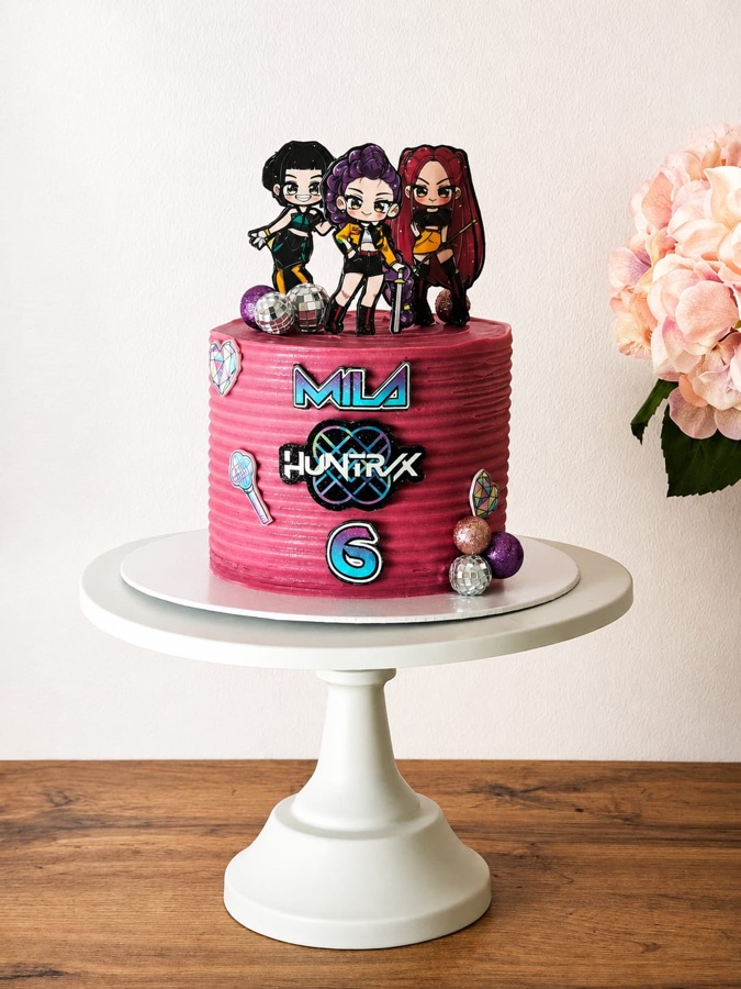 Tarta rosa de dos alturas con las figuras de un grupo musical y detalles metálicos