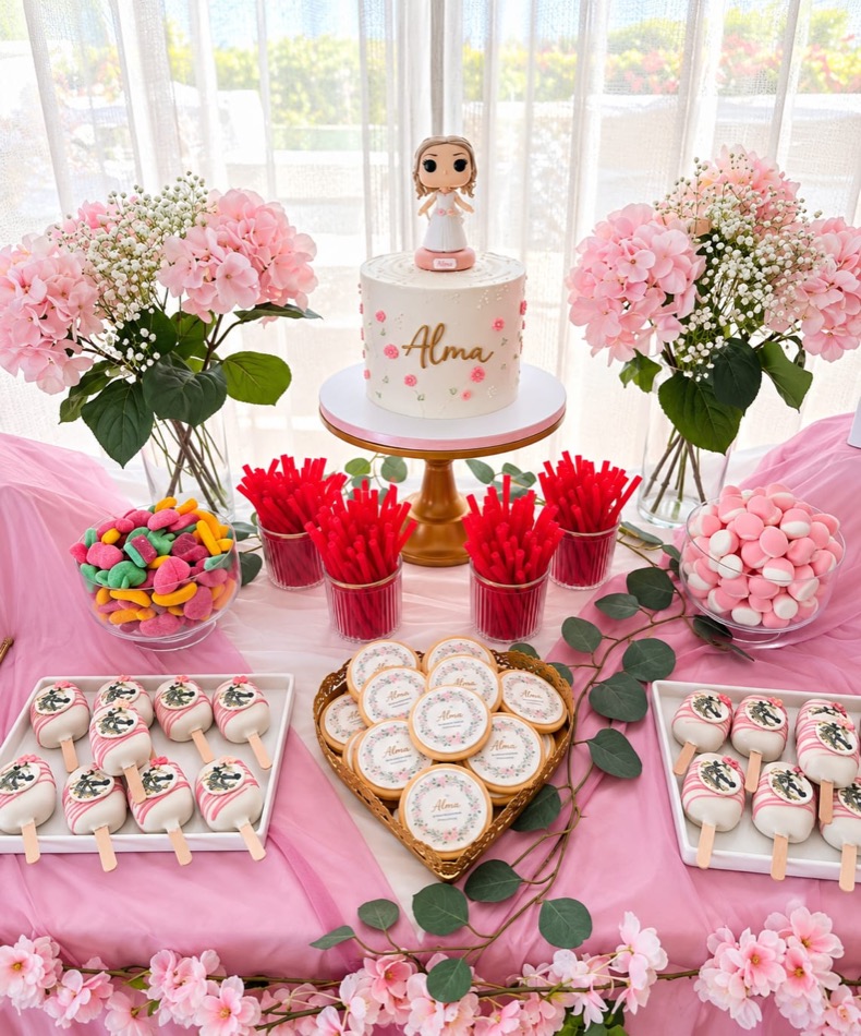 Mesa con tarta, hortensias, galletas decoradas, cakesicles, gominolas y vasos de regaliz