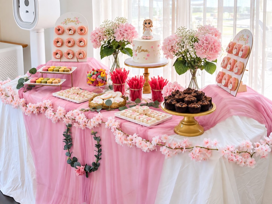 Mesa larga con panel de donuts, tarta, macarons, muffins de chocolate, galletas y gominolas