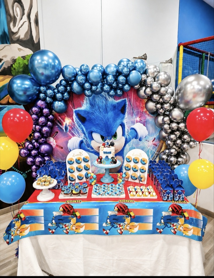 Mesa infantil con temática de Sonic: tarta con figura, paneles de donuts decorados, galletas y macarons
